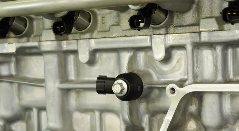 A knock sensor is shown installed on an engine block.
