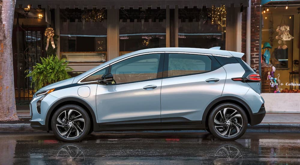 A silver 2022 Chevy Bolt EV is shown parked on a road near a store.
