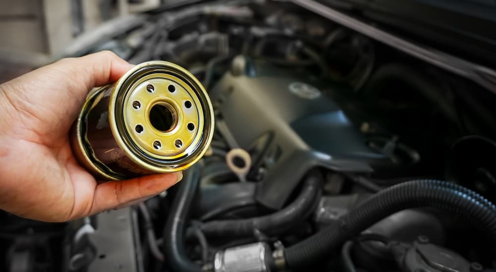 An oil filter is shown being held by a mechanic during a routine oil change.