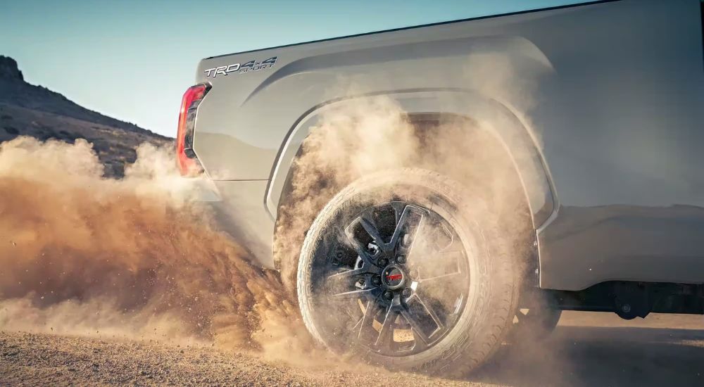 The wheel of a 2023 Toyota Tundra is shown with dirt in the air around it.
