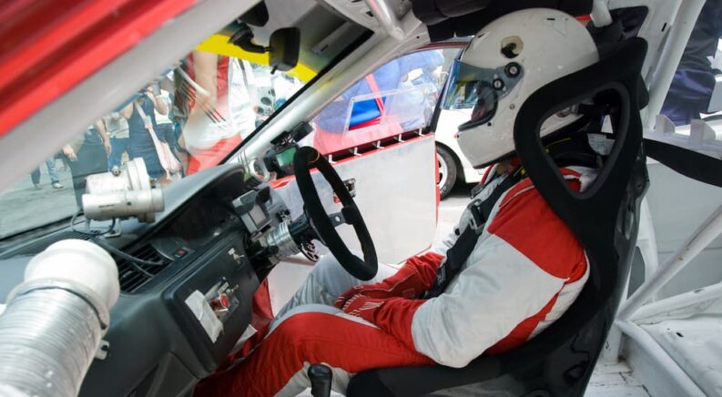 A driver is shown sitting on a racing seat.