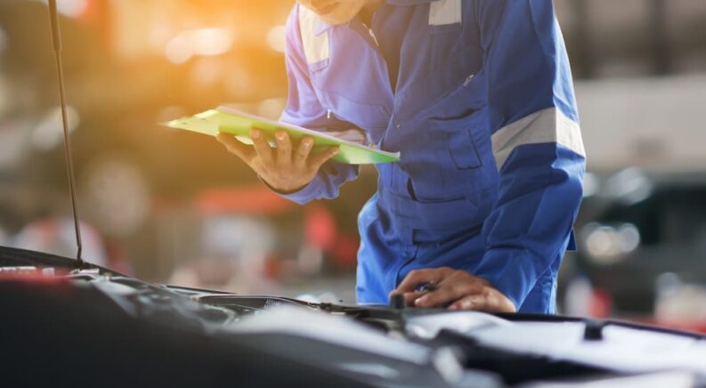 A mechanic is shown checking his Honda car service maintenance checklist.