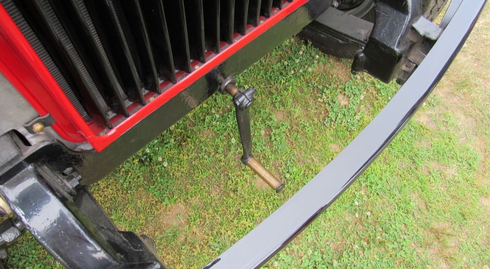 A hand-operated crank starter is shown on a red vehicle.
