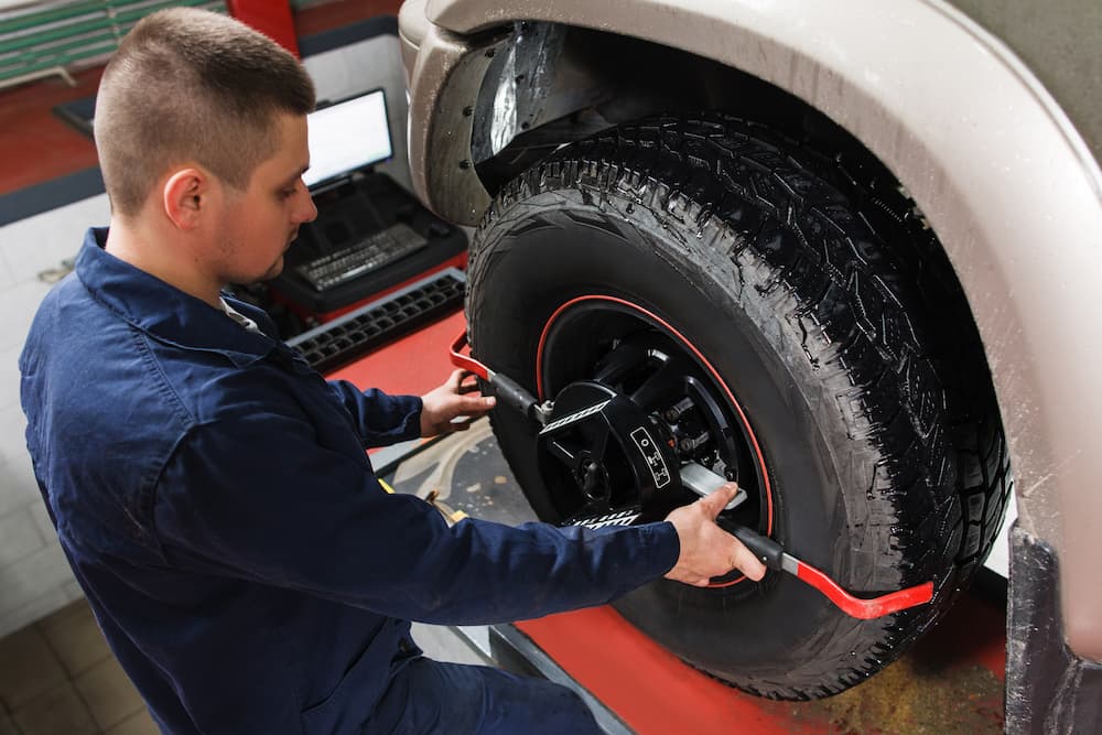 A mechanic performing a tire alignment is shown.