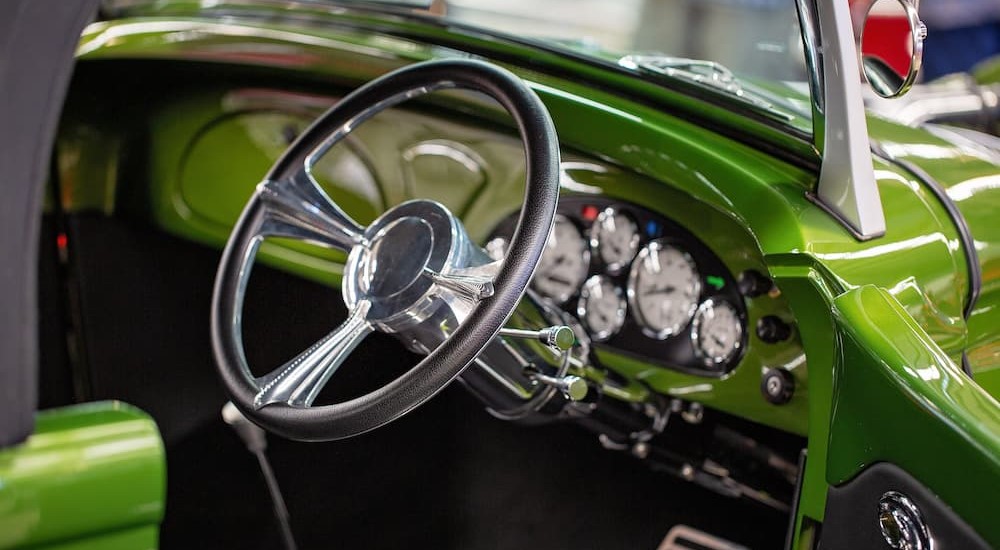 An aftermarket steering wheel is shown inside of a green hotrod.