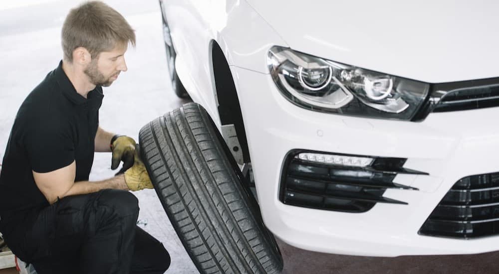 A mechanic is shown looking at a vehicles tire.
