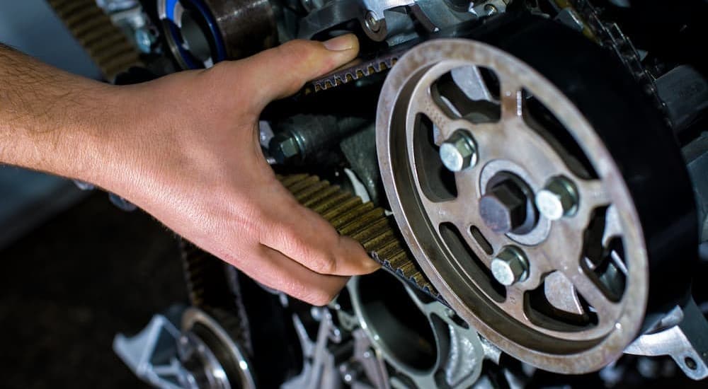 A mechanic is shown holding a timing belt.