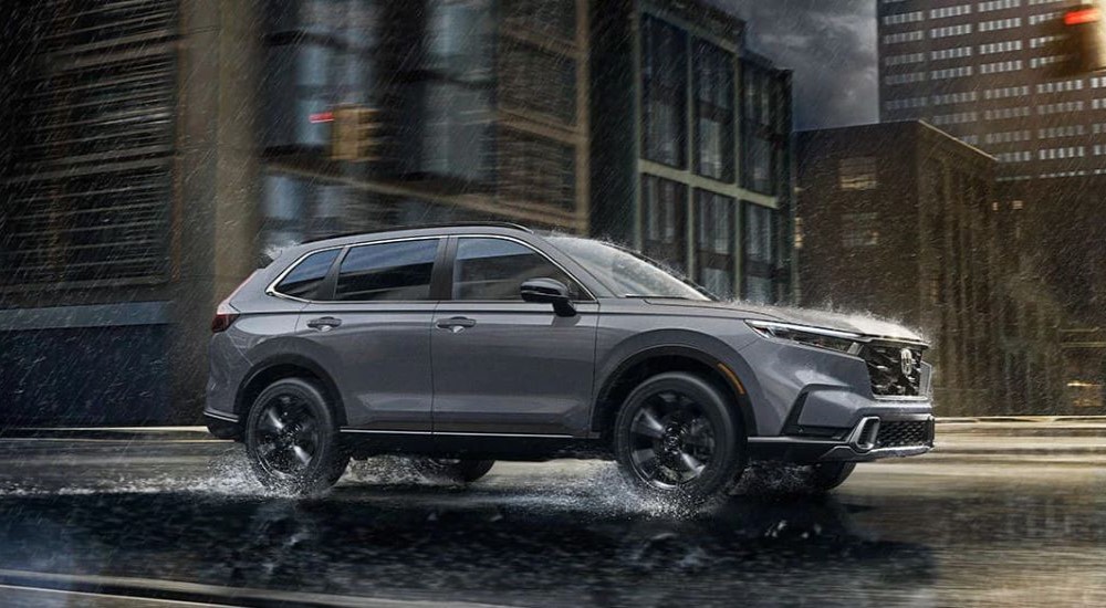 A gray Honda CR-V Sport Touring is shown driving on a wet road. 