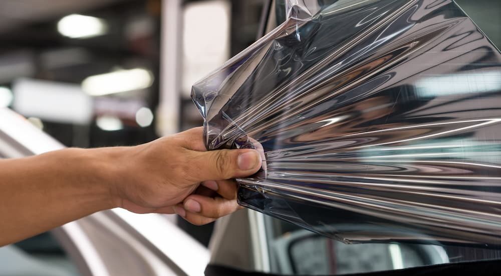 To sell your car a person is shown removing the window tint.