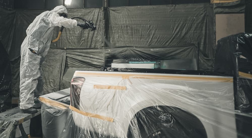 A specialist is shown using a spray gun on a trucks bed liner.