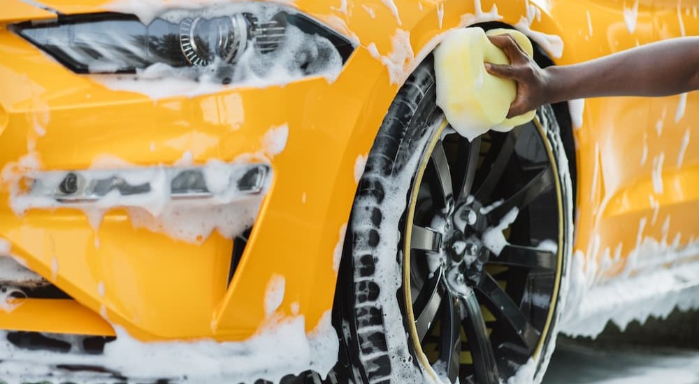 A person is shown using a sponge to clean a tire.