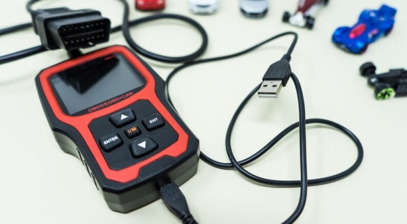 A black and red OBD2 scanner is shown.