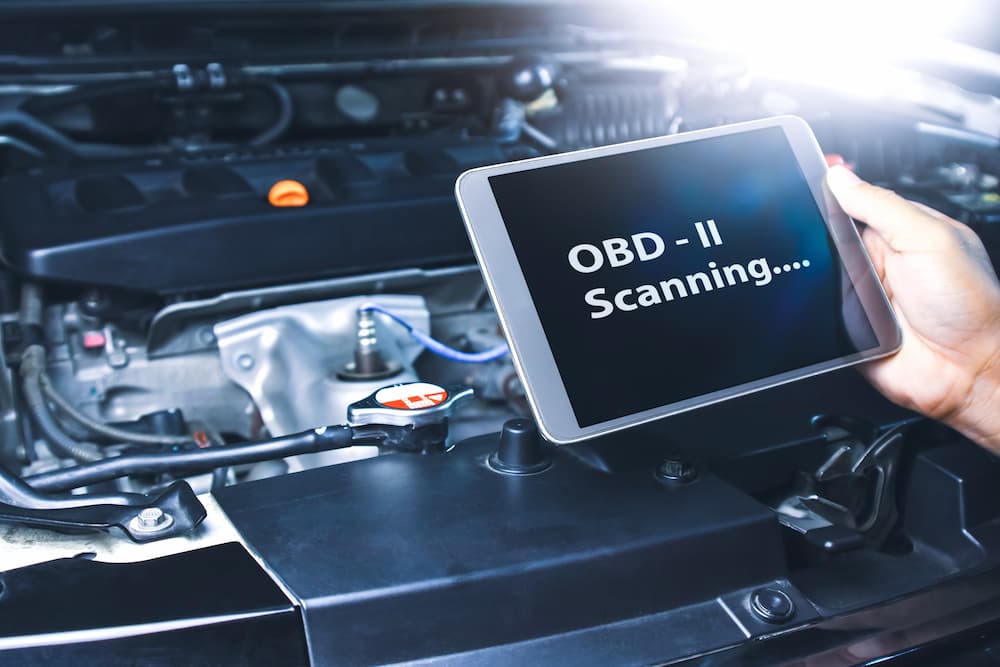 An OBD2 scanner is shown scanning.