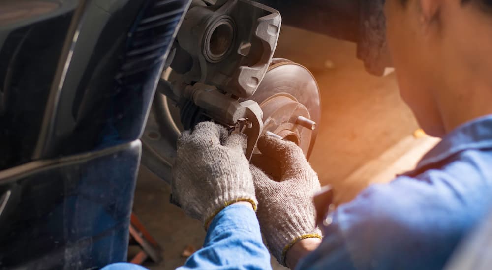 A mechanic is shown working on the brakes of a vehicle.