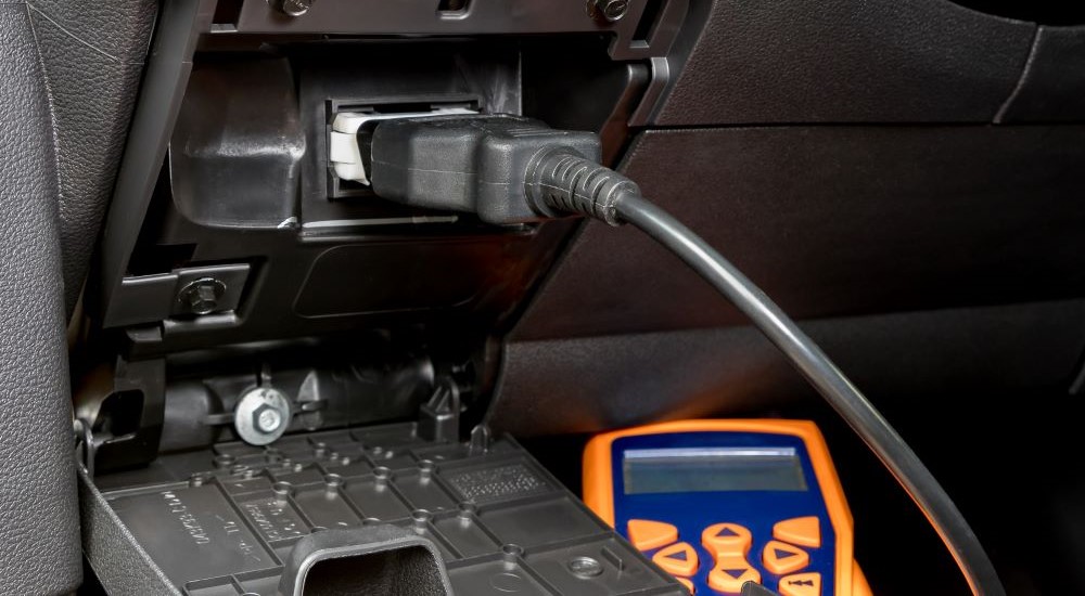 An OBD2 reader is shown plugged into a vehicle.
