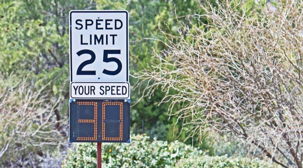 A drivers speed is shown under a speed limit sign.