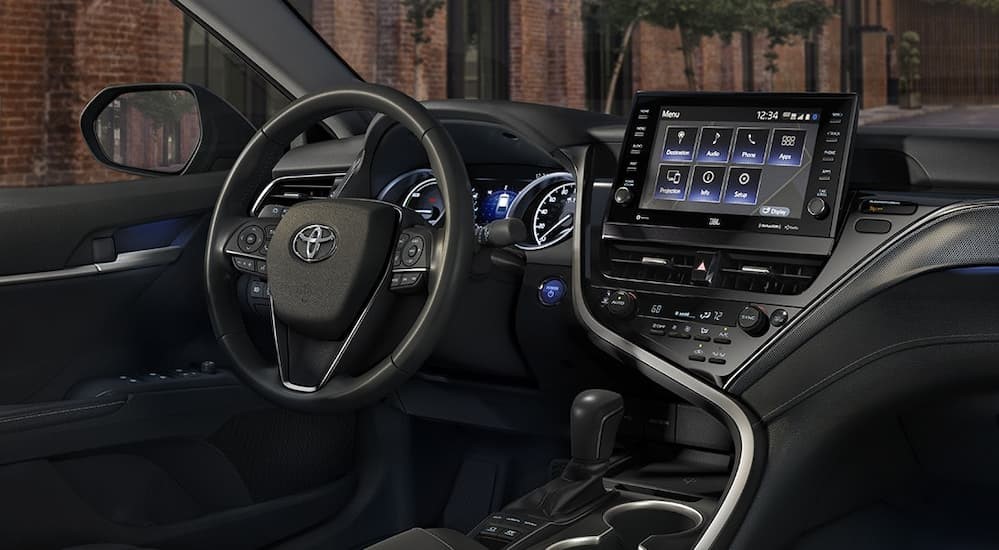 The black interior and dash of a 2021 Toyota Camry Hybrid is shown.