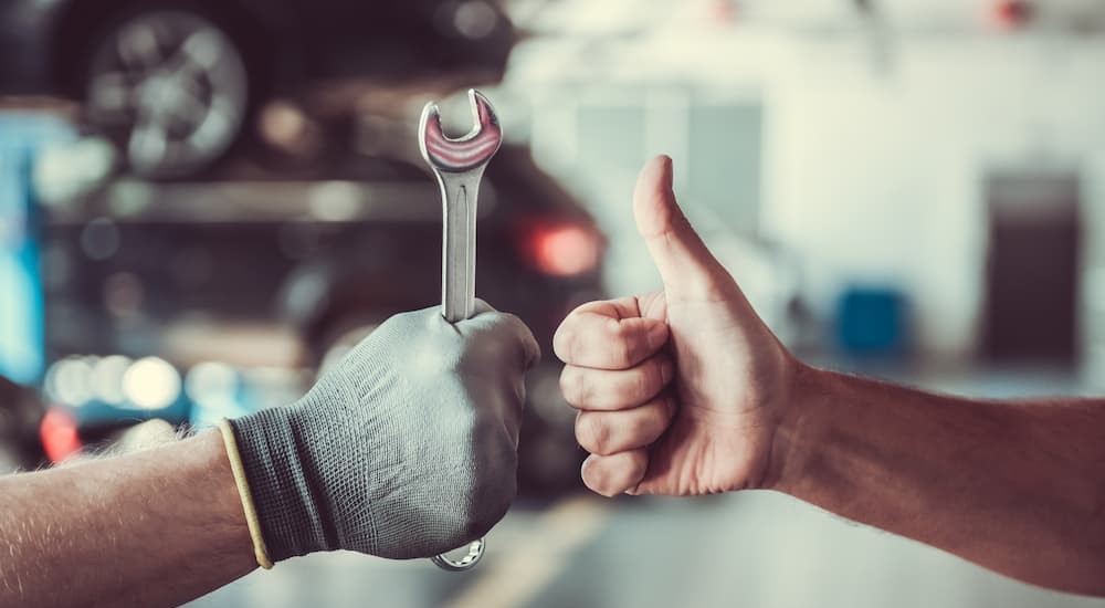 A mechanic is shown holding up a wrench and a person is shown giving a thumbs up.