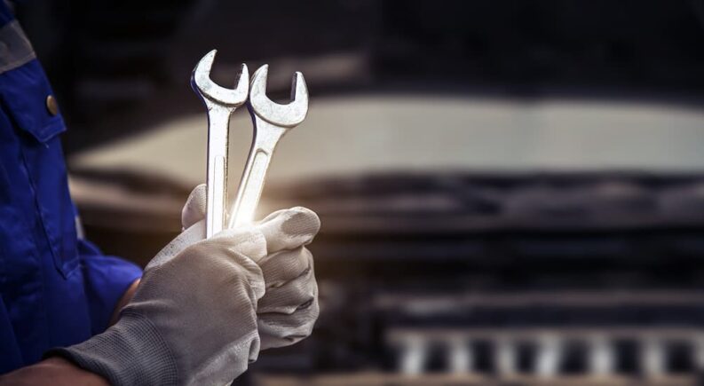 A mechanic is shown holding two wrenches at a Toyota service center.