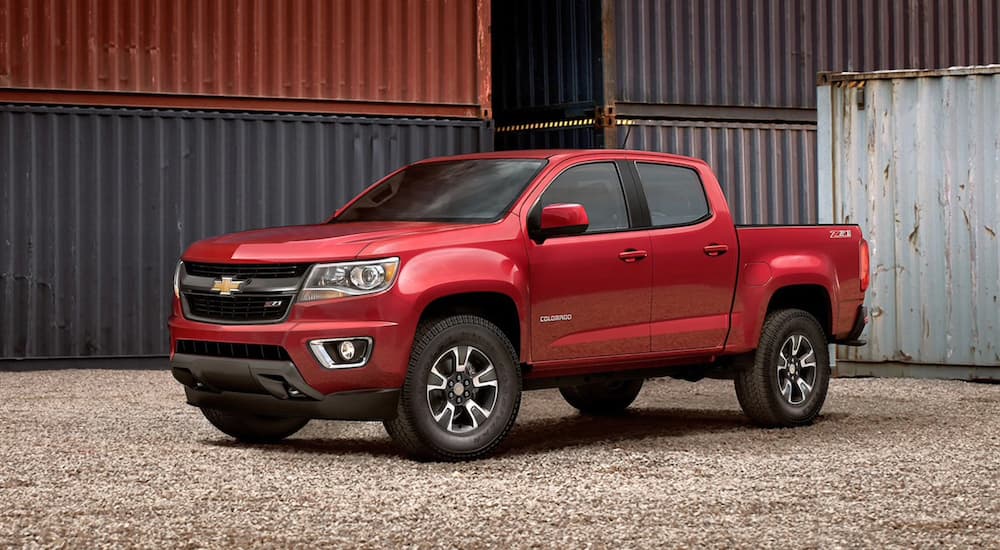 A red 2020 Chevy Colorado Z71 is shown parked near shipping containers after visiting a used truck dealer.