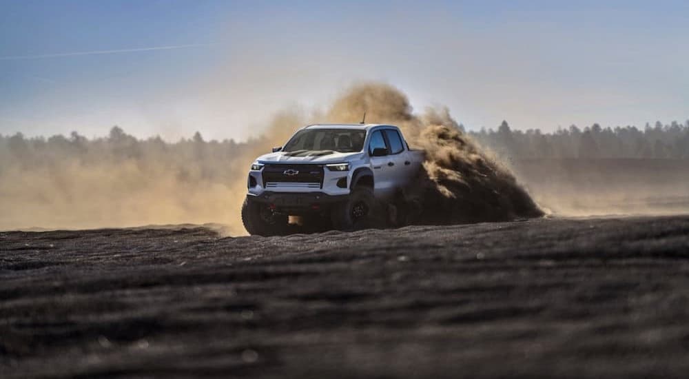 A white 2024 Chevy Colorado ZR2 Bison is shown driving off-road on dirt.