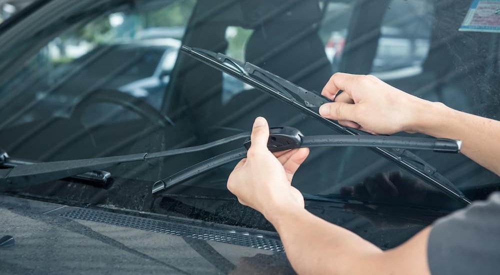 A person is shown changing their windshield wiper blade.