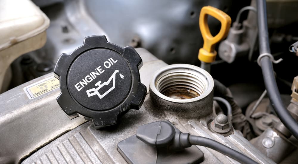 An engine oil cap is shown balanced on an engine.
