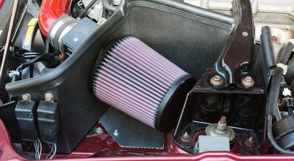A pink and black cold air intake is shown in an engine bay.