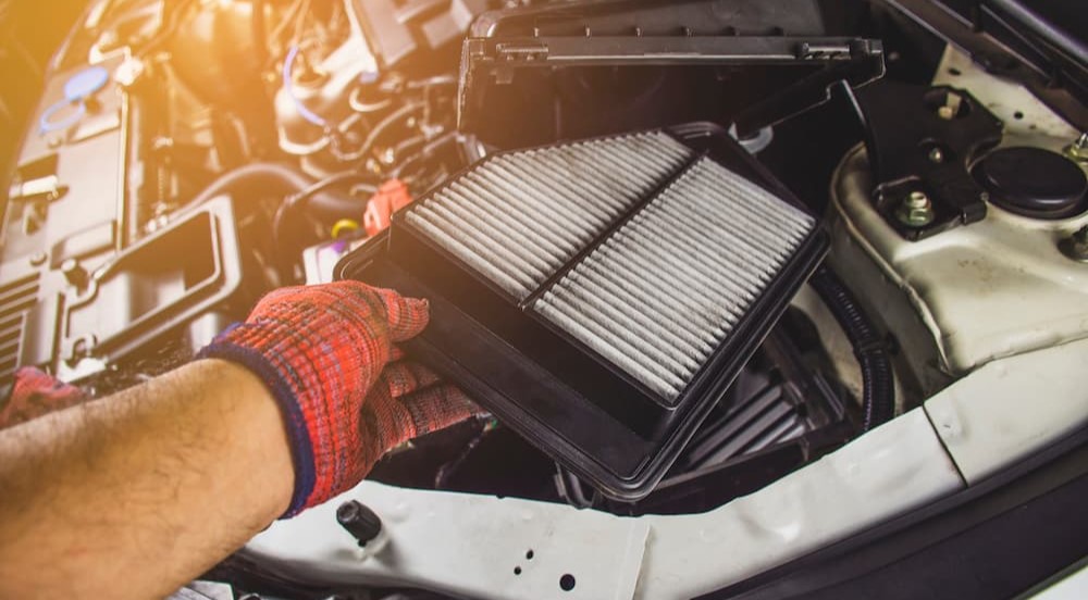 A mechanic is shown replacing a dirty engine air filter.