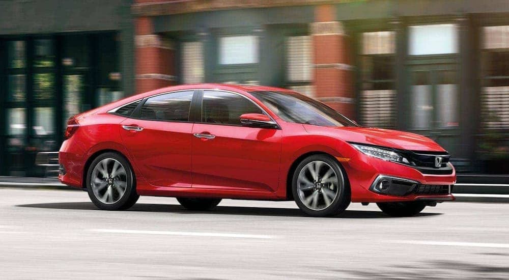 A red 2020 Honda Civic Touring is shown driving on a city street.