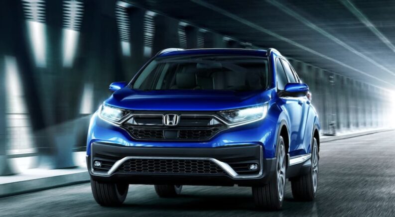 A blue 2022 Honda CR-V is shown driving on a city road.