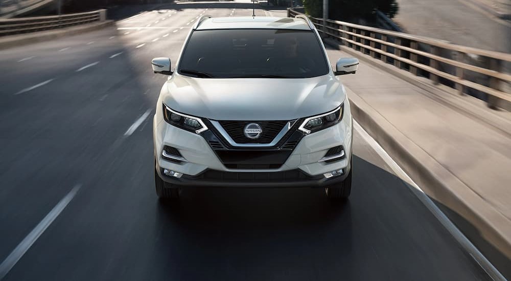 A white 2022 Nissan Rogue is shown driving on a bridge.