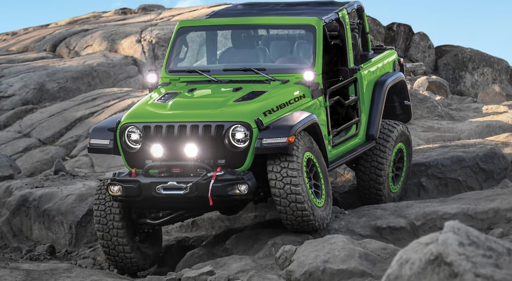 One of many popular used Jeeps, a green 2018 Jeep Wrangler JL, is shown off-roading.