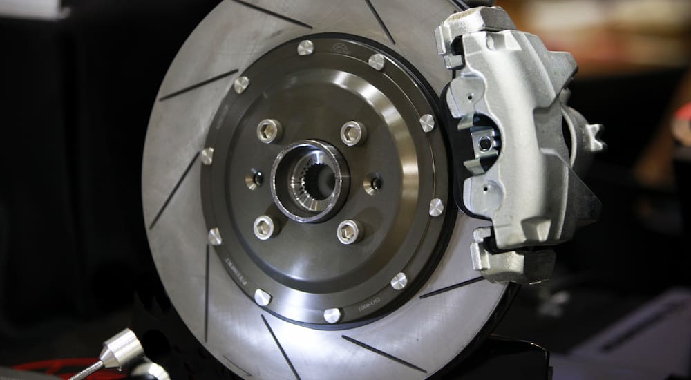 Close up of a slotted brake rotor with silver caliper.