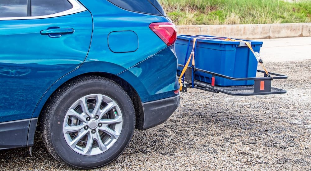 A blue vehicle is shown using a hitch-mounted cargo rack.