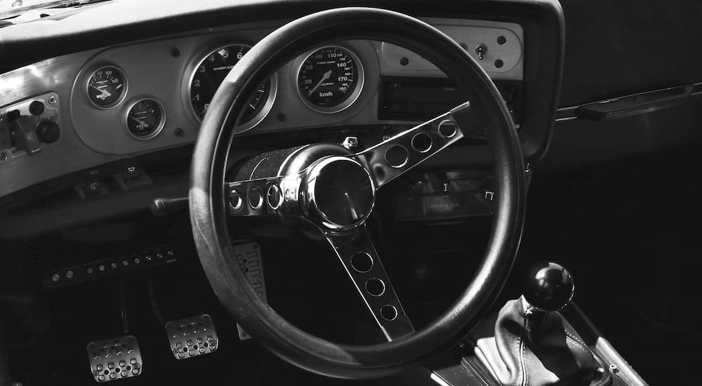 The aftermarket steering wheel in a race car, in black and white.