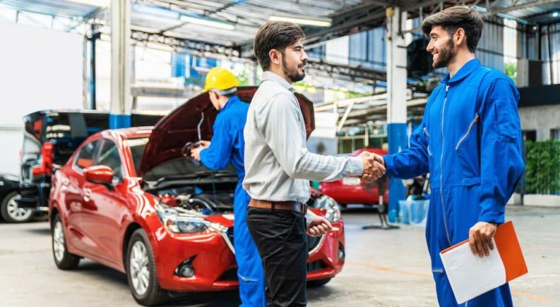 A mechanic is shown shaking the hand of a customer.