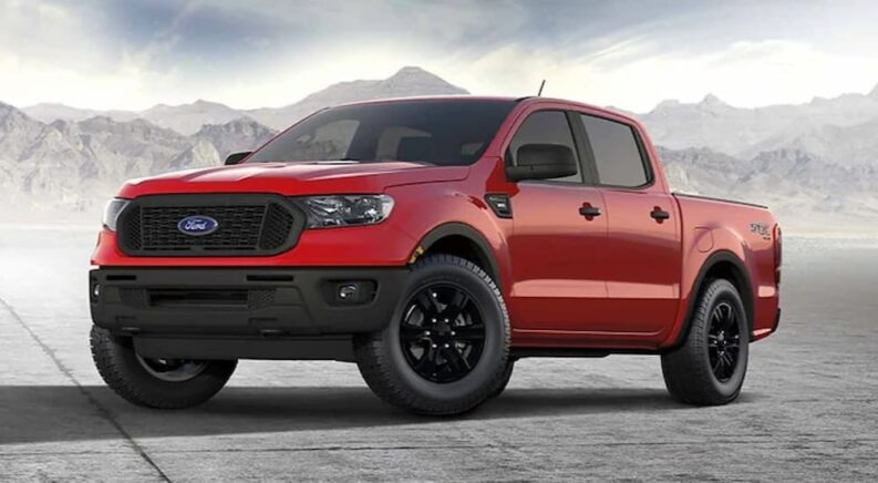 A red 2023 Ford Ranger STX is shown parked near a mountain after visiting a used Ford truck dealer.