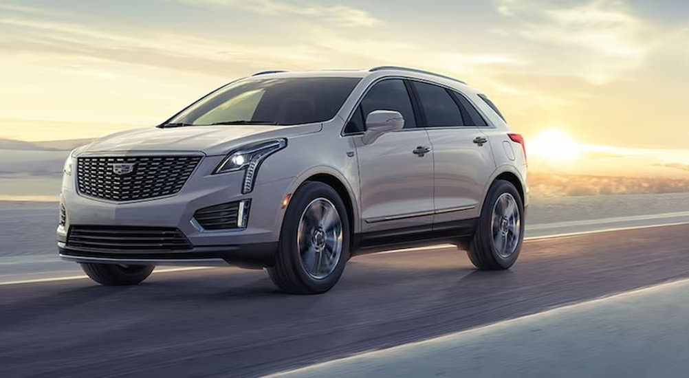 A white 2024 Cadillac XT5 is shown driving on a sunny day.