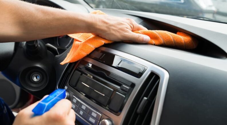 A person is shown cleaning the dash in a vehicle at an auto service center near Sandy Springs.