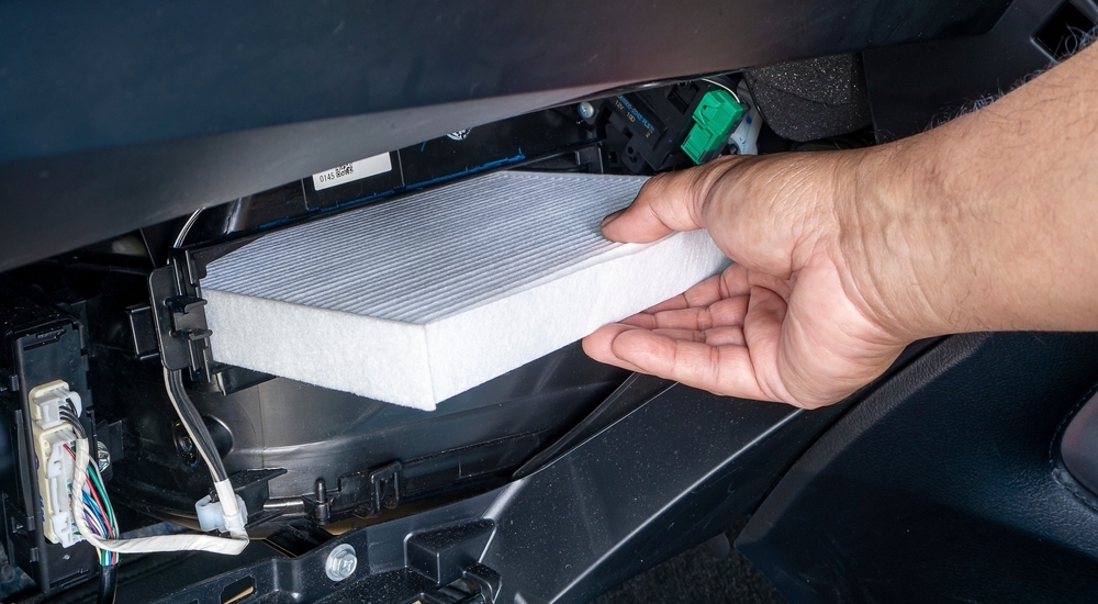 A mechanic pulling out a cabin air filter.