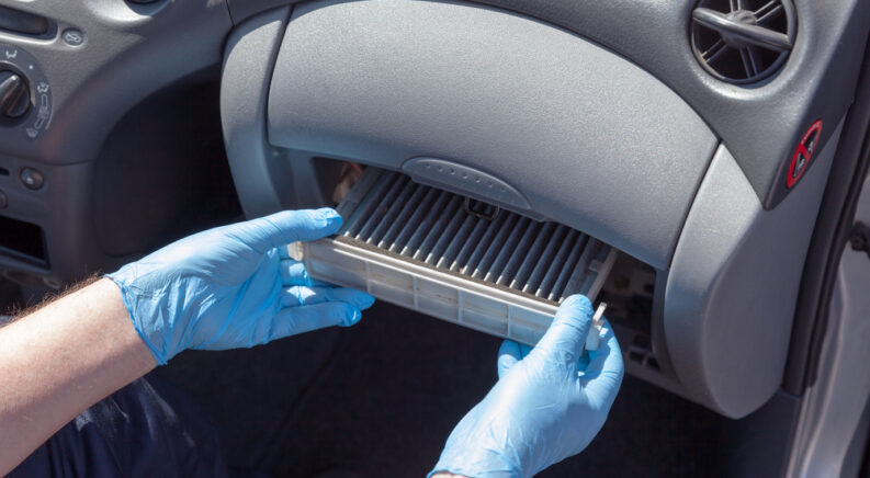 A mechanic performing a car air filter replacement.