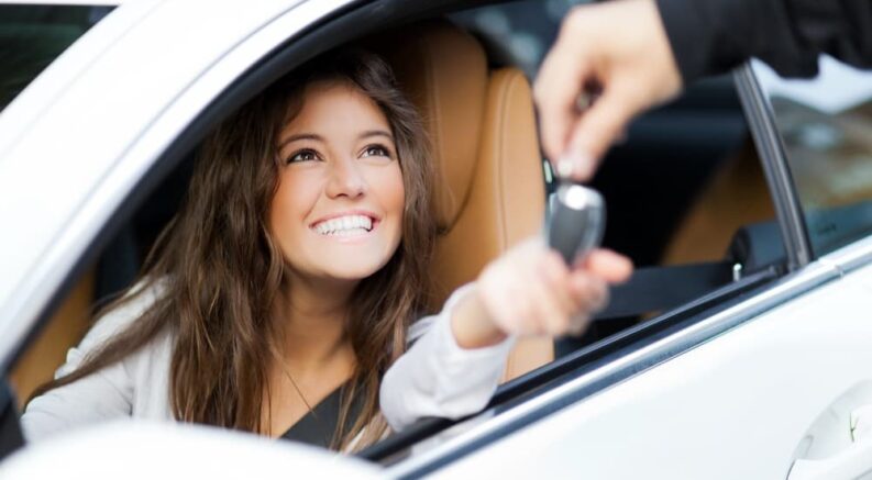 A person is shown smiling after receiving a key fob near a Buick service center.