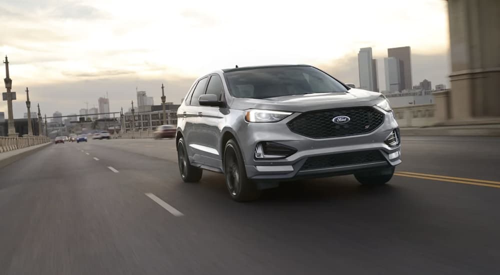 A silver 2022 Ford Edge is shown driving on a city road.