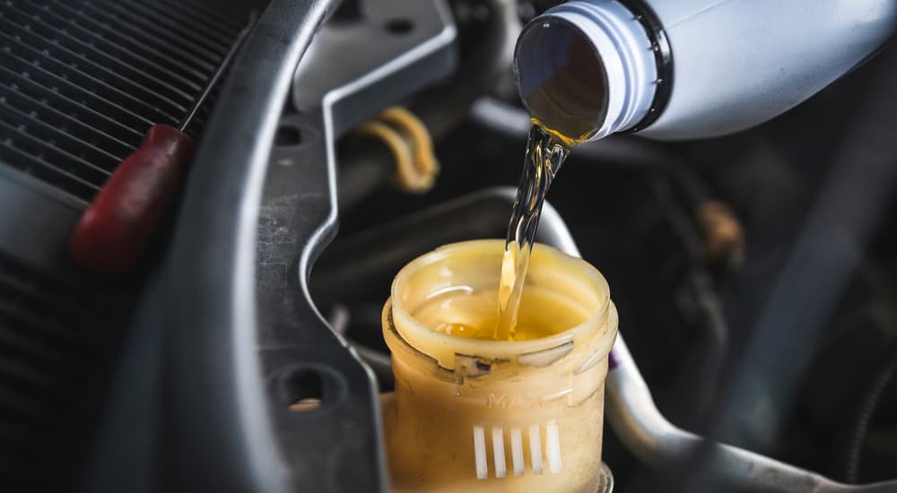 A canister of brake fluid is shown being poured into an engine.