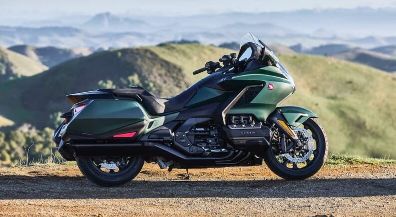 A green 2024 Honda Gold Wing is shown parked near mountains.