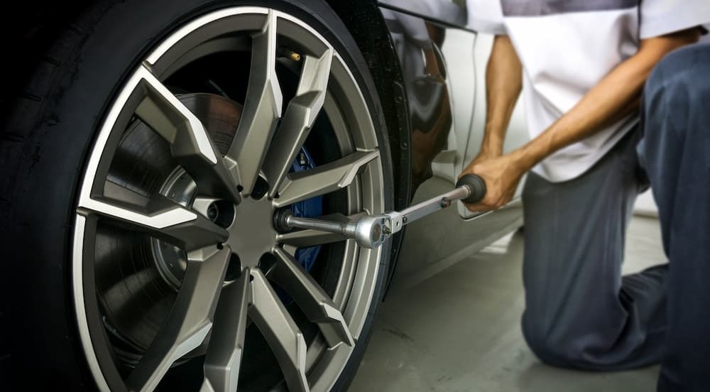 A person is shown using a torque wrench on a wheel.
