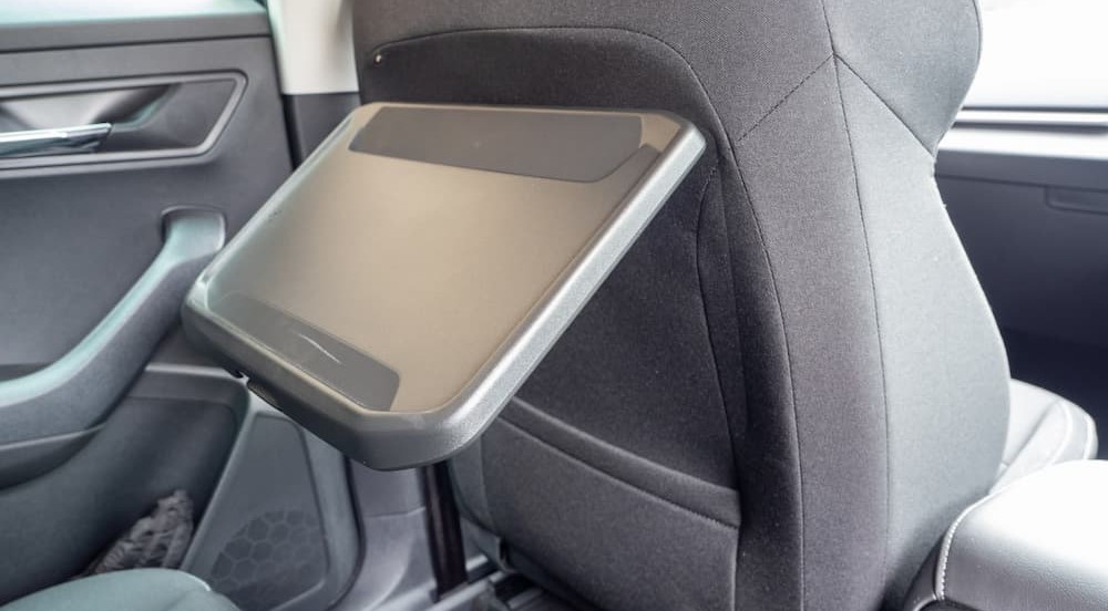 A tray table is shown on the back of a seat in a vehicle.