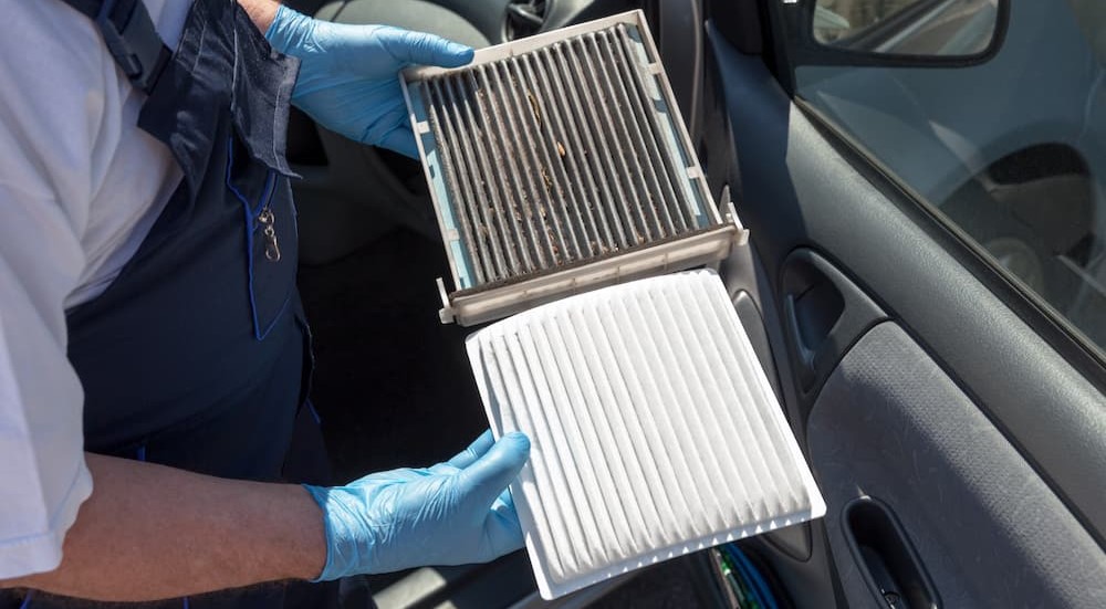A mechanic is shown holding a dirty and a clean air filter.