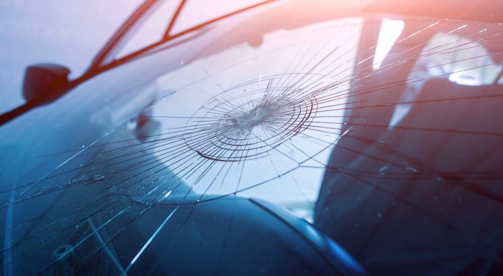 A windshield is shown with a spider-web crack.